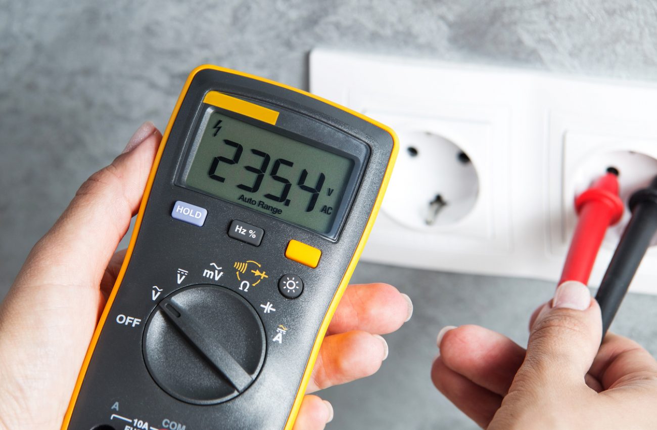 Woman checking voltage in power socket with tester close-up. Housewife hands with multimeter.
